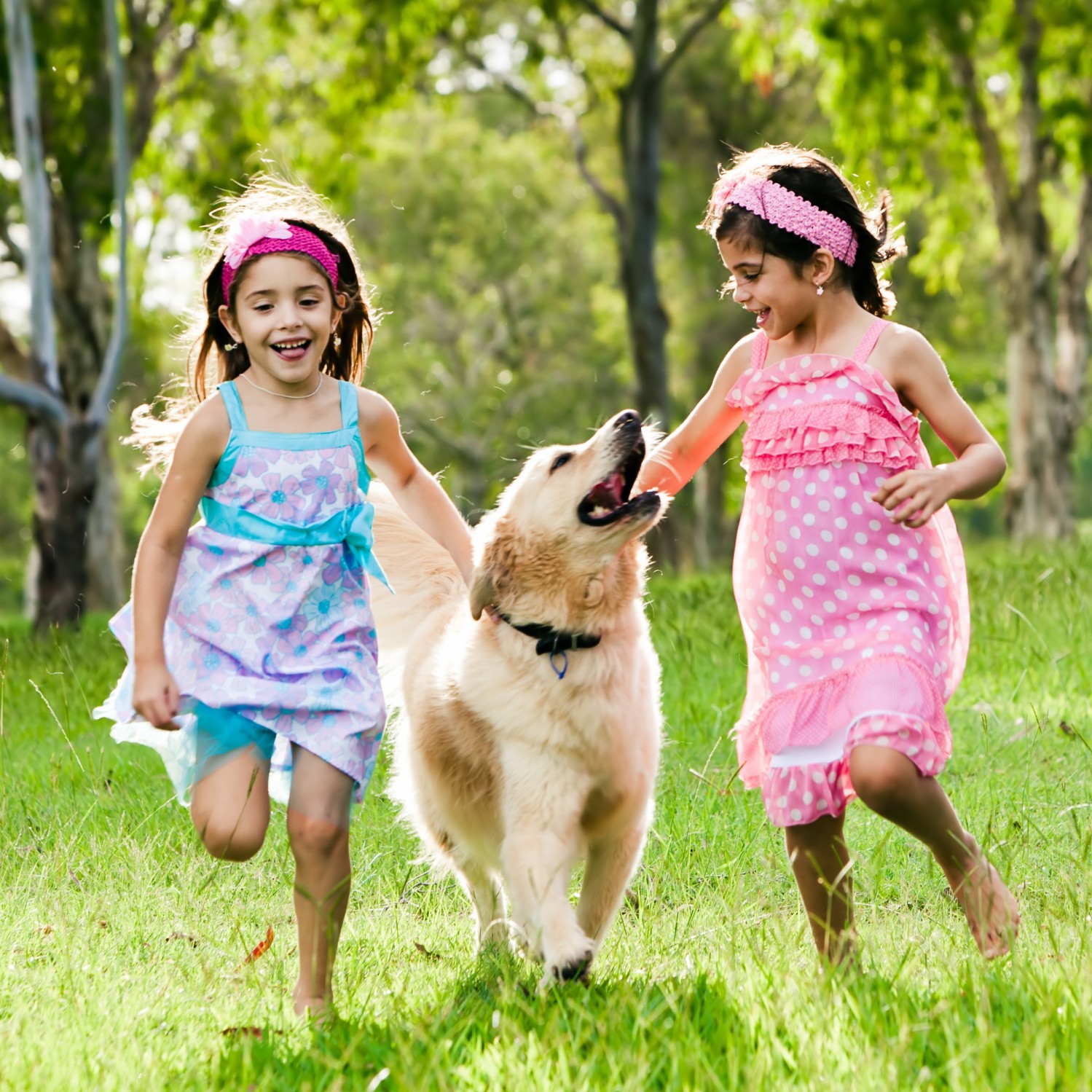 Two girls running in the grass with a dog